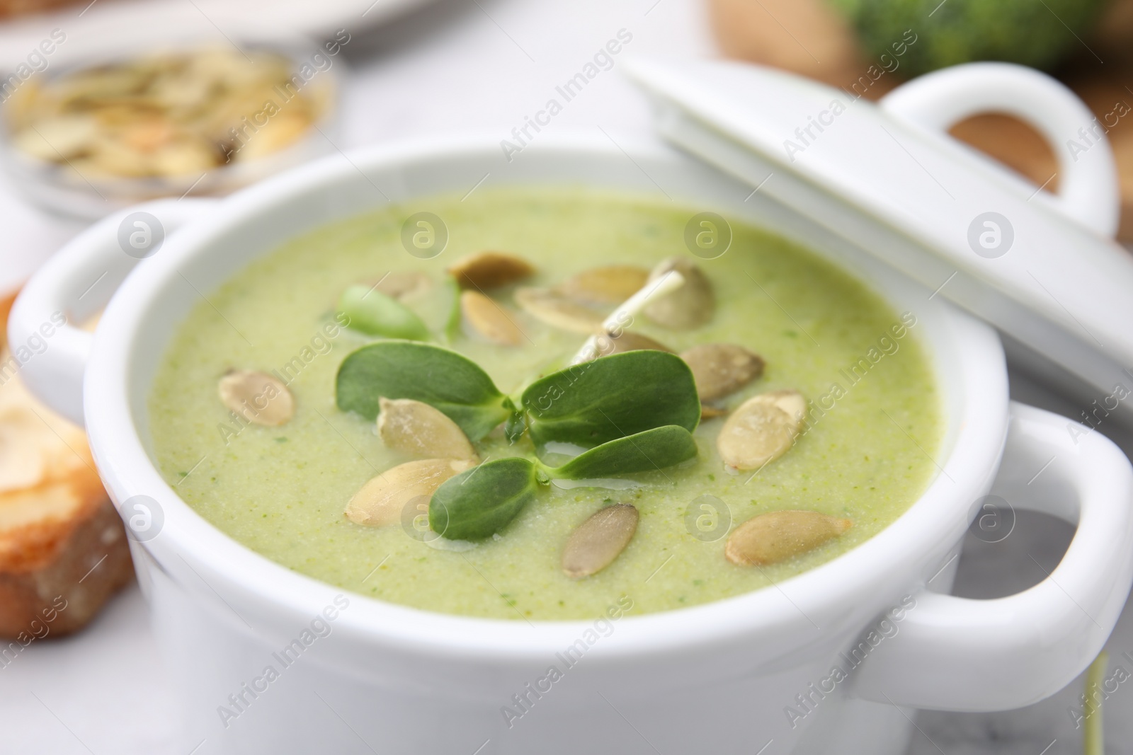 Photo of Delicious broccoli cream soup with pumpkin seeds in bowl, closeup