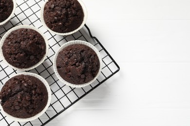 Photo of Tasty chocolate muffins on white wooden table, top view. Space for text