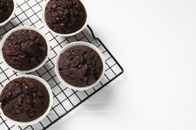 Tasty chocolate muffins on white wooden table, top view. Space for text