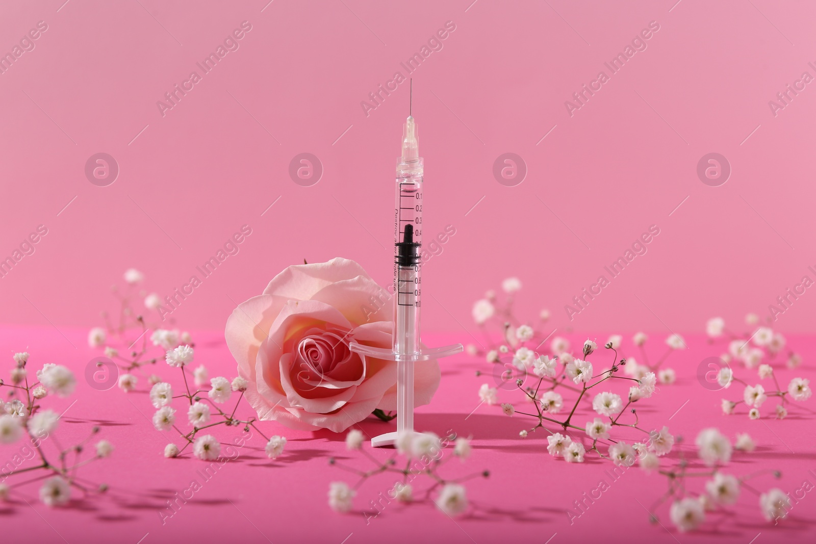 Photo of Cosmetology. Medical syringe, rose and gypsophila flowers on pink background