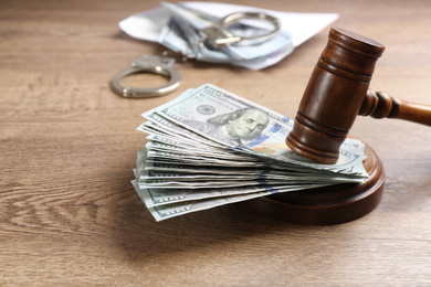 Photo of Dollar bills and gavel on wooden table. Bribe concept