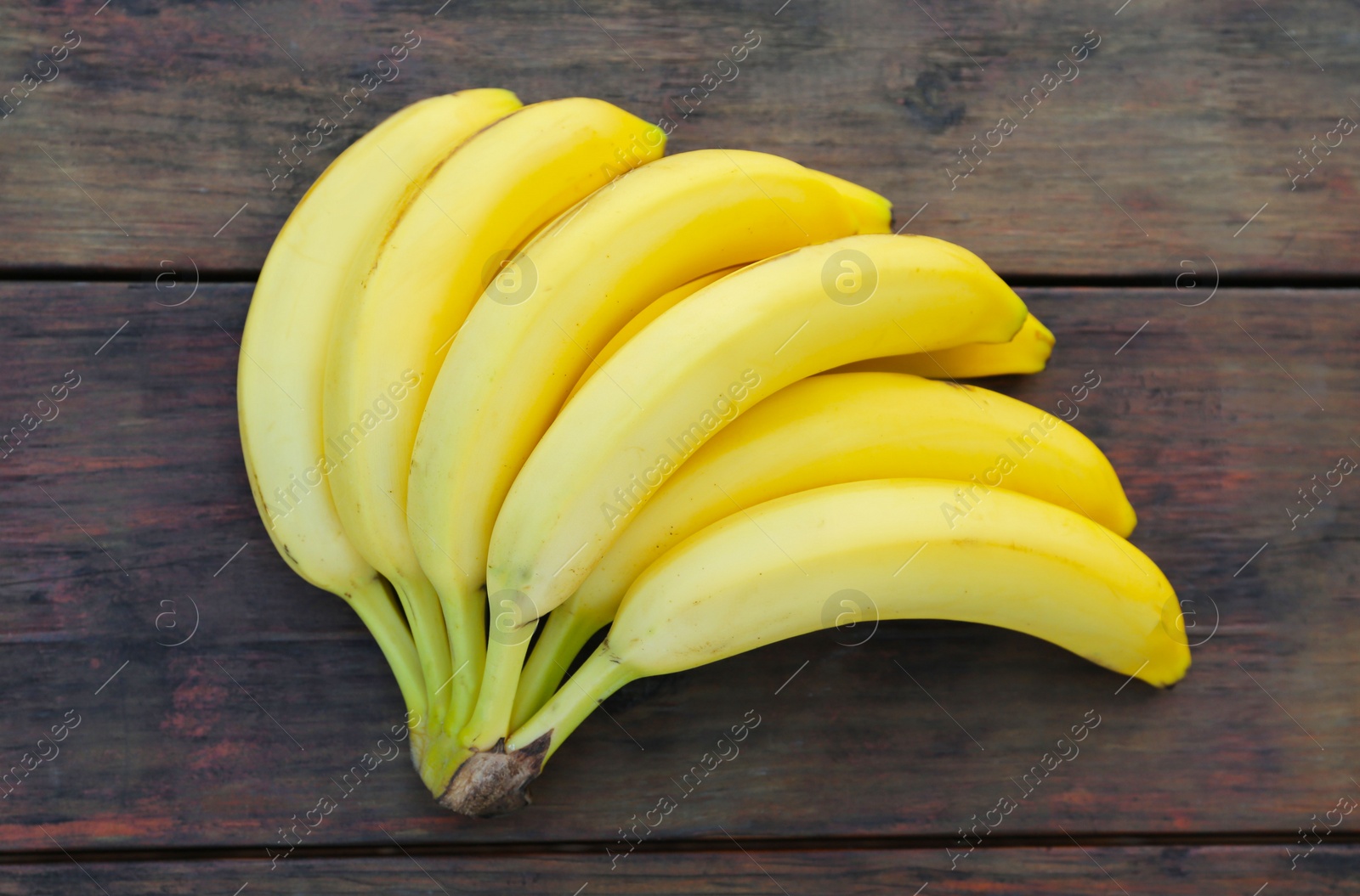 Photo of Bunch of ripe yellow bananas on wooden table, top view