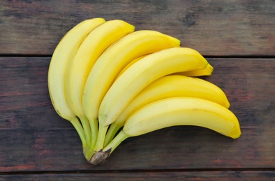 Photo of Bunch of ripe yellow bananas on wooden table, top view