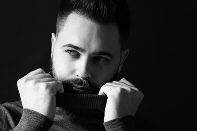 Portrait of handsome bearded man on dark background, space for text. Black and white effect