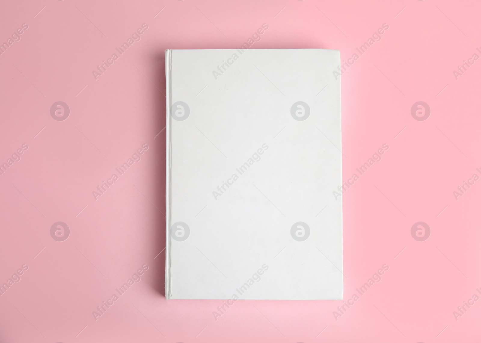 Photo of Book with blank cover on pink background, top view