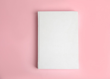 Photo of Book with blank cover on pink background, top view