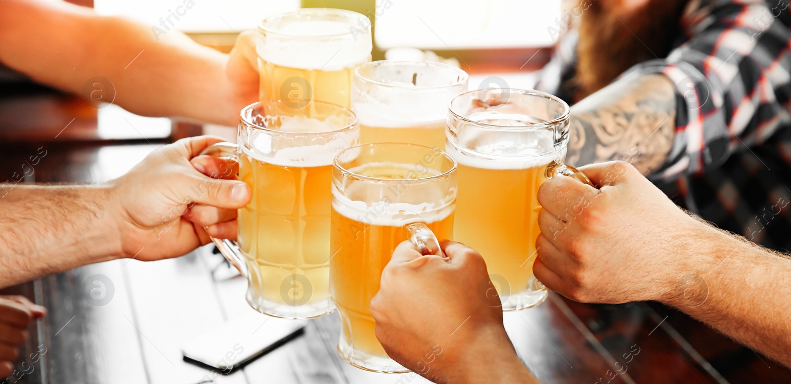 Image of Group of friends toasting with beer in pub, closeup. Banner design