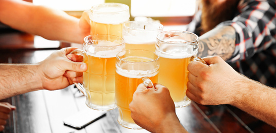 Image of Group of friends toasting with beer in pub, closeup. Banner design