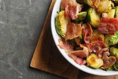 Photo of Delicious roasted Brussels sprouts with bacon served on grey table, top view