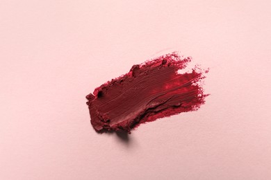 Photo of Smear of beautiful lipstick on light background, top view