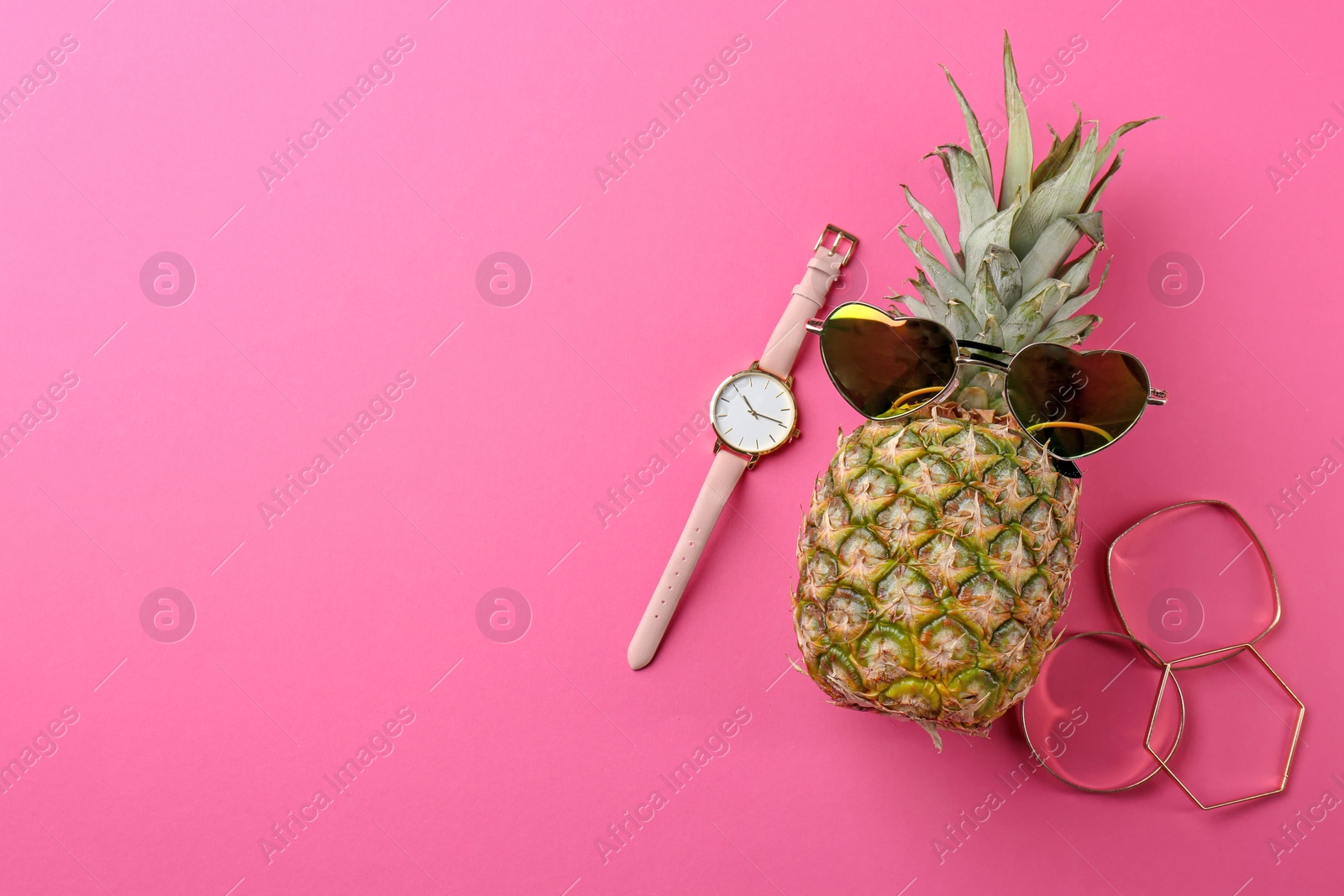 Photo of Funny pineapple with sunglasses, bracelets and watch on color background