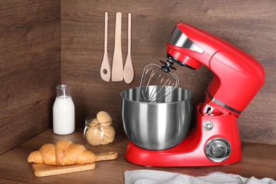 Photo of Modern red stand mixer, croissant and cookies on wooden table