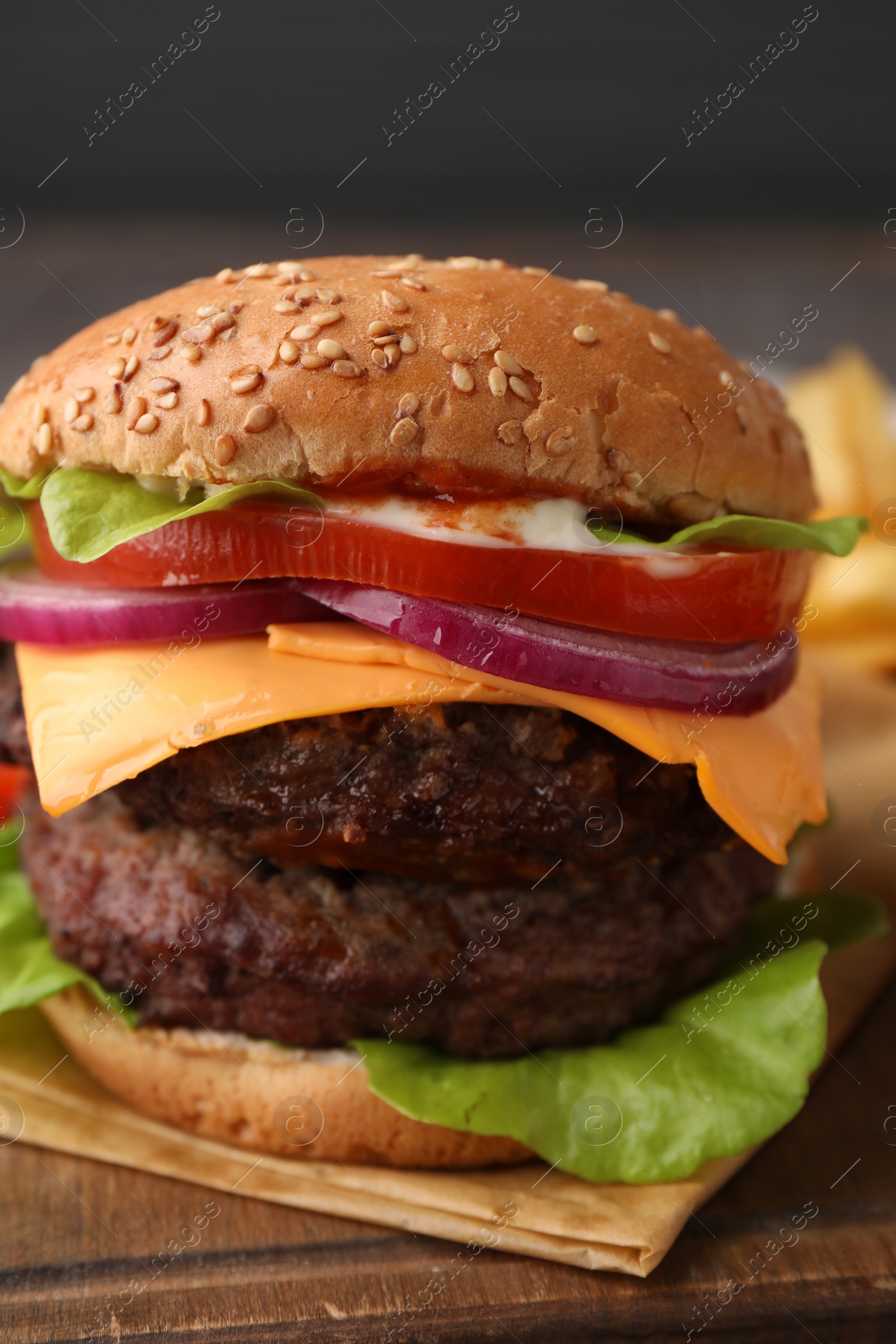 Photo of Tasty cheeseburger with patties on wooden board, closeup