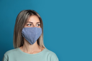 Young woman in protective face mask on blue background. Space for text