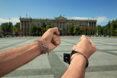 Photo of Man in handcuffs on city street, closeup