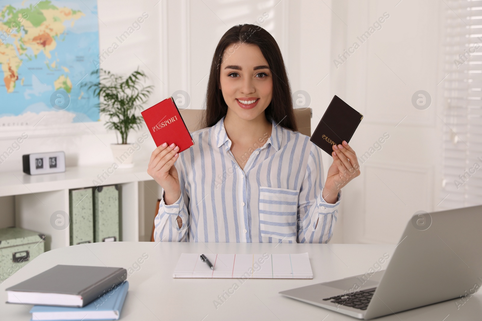 Photo of Happy manager holding passports at desk in travel agency