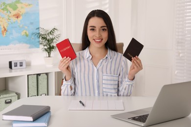 Happy manager holding passports at desk in travel agency