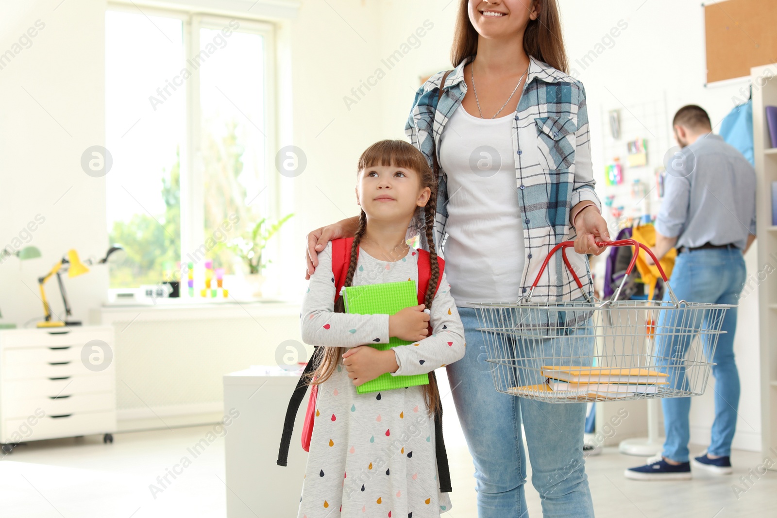 Photo of Little girl choosing school supplies with mother in stationery shop