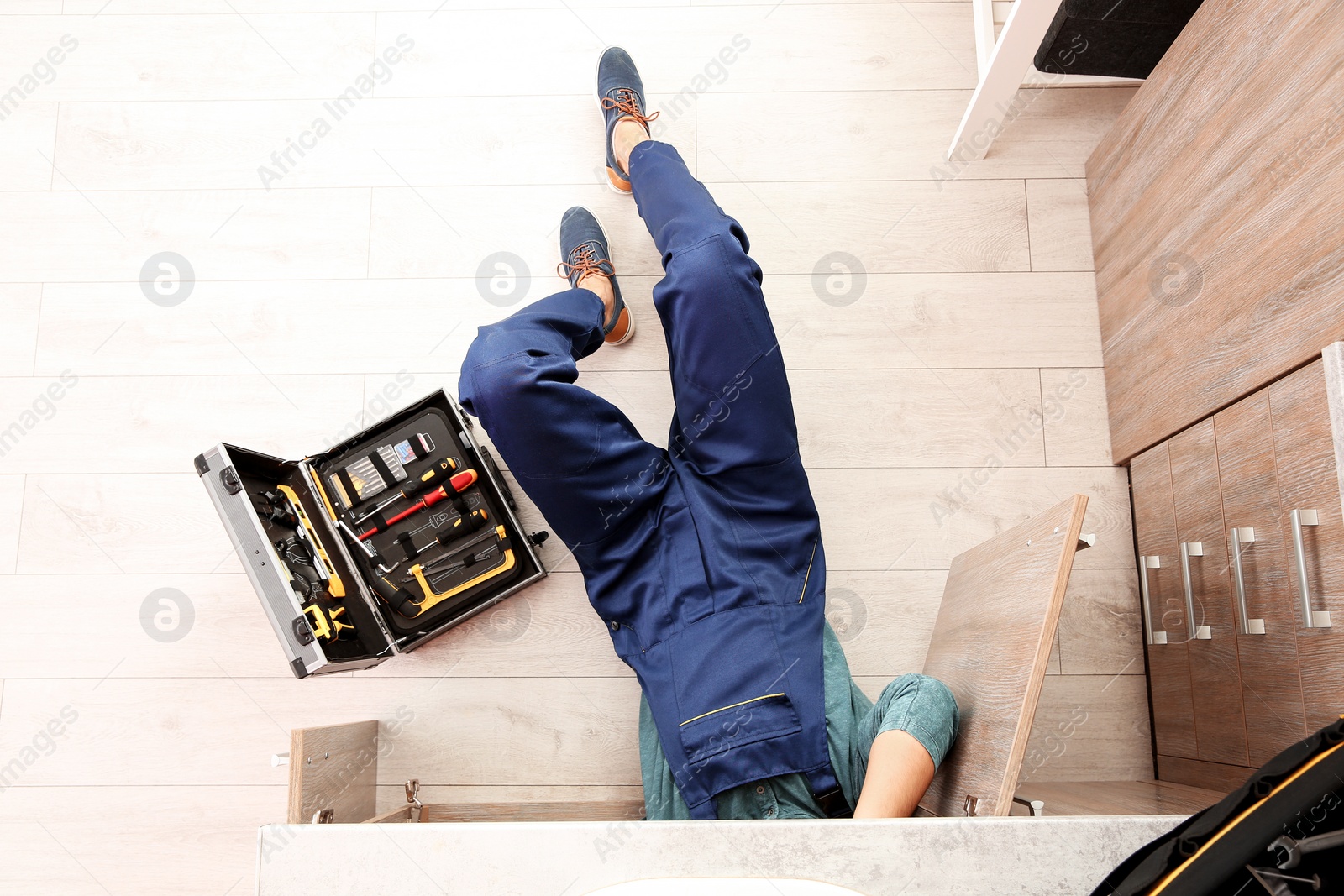 Photo of Male plumber repairing kitchen sink, top view