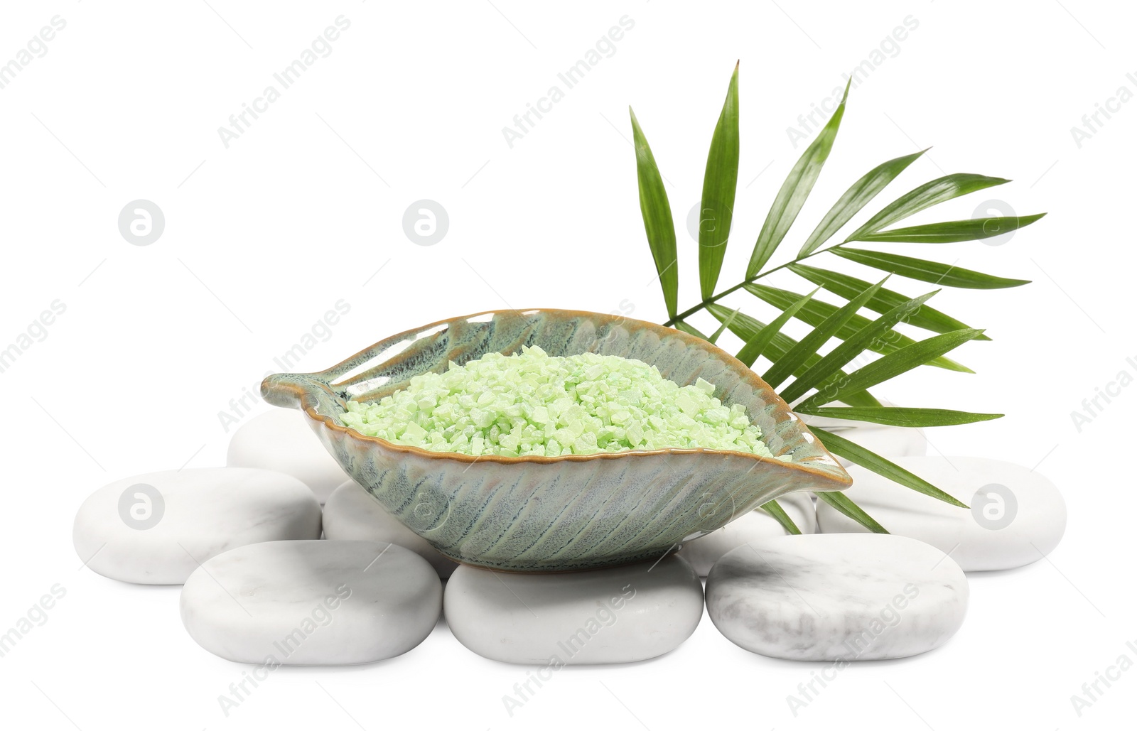 Photo of Green sea salt in bowl, spa stones and palm leaves isolated on white