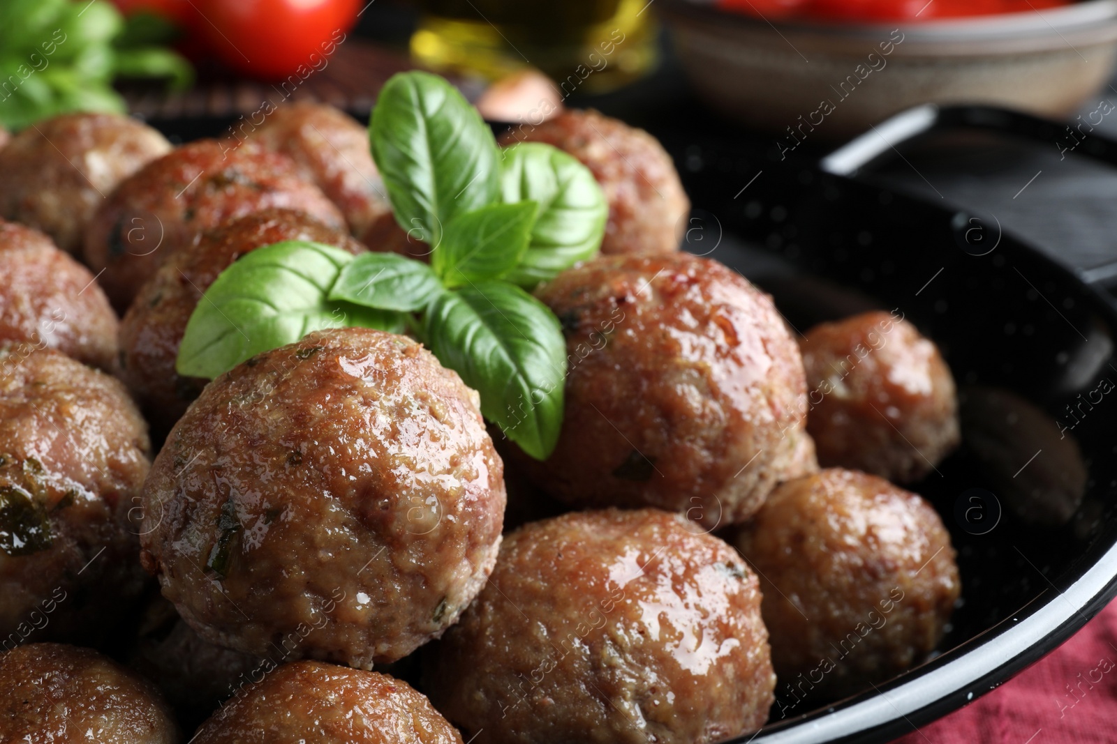 Photo of Tasty cooked meatballs and basil on table, closeup
