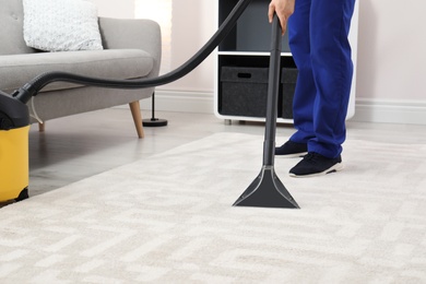 Photo of Man removing dirt from carpet with vacuum cleaner indoors, closeup. Space for text