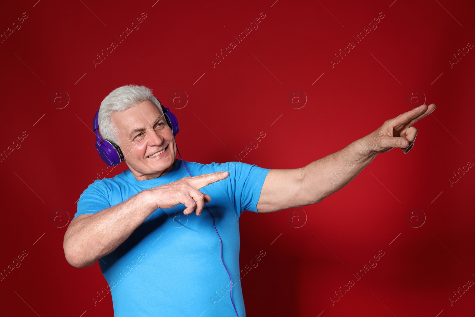 Photo of Mature man enjoying music in headphones on color background