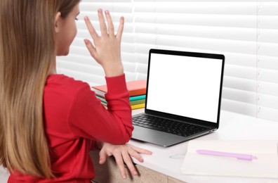Photo of E-learning. Girl raising her hand to answer during online lesson at table indoors, closeup