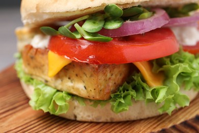 Delicious burger with tofu and fresh vegetables on wooden board, closeup