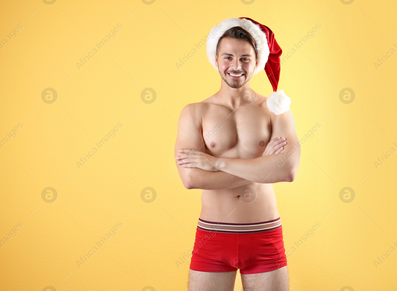 Photo of Shirtless young Santa Claus with sexy body on color background