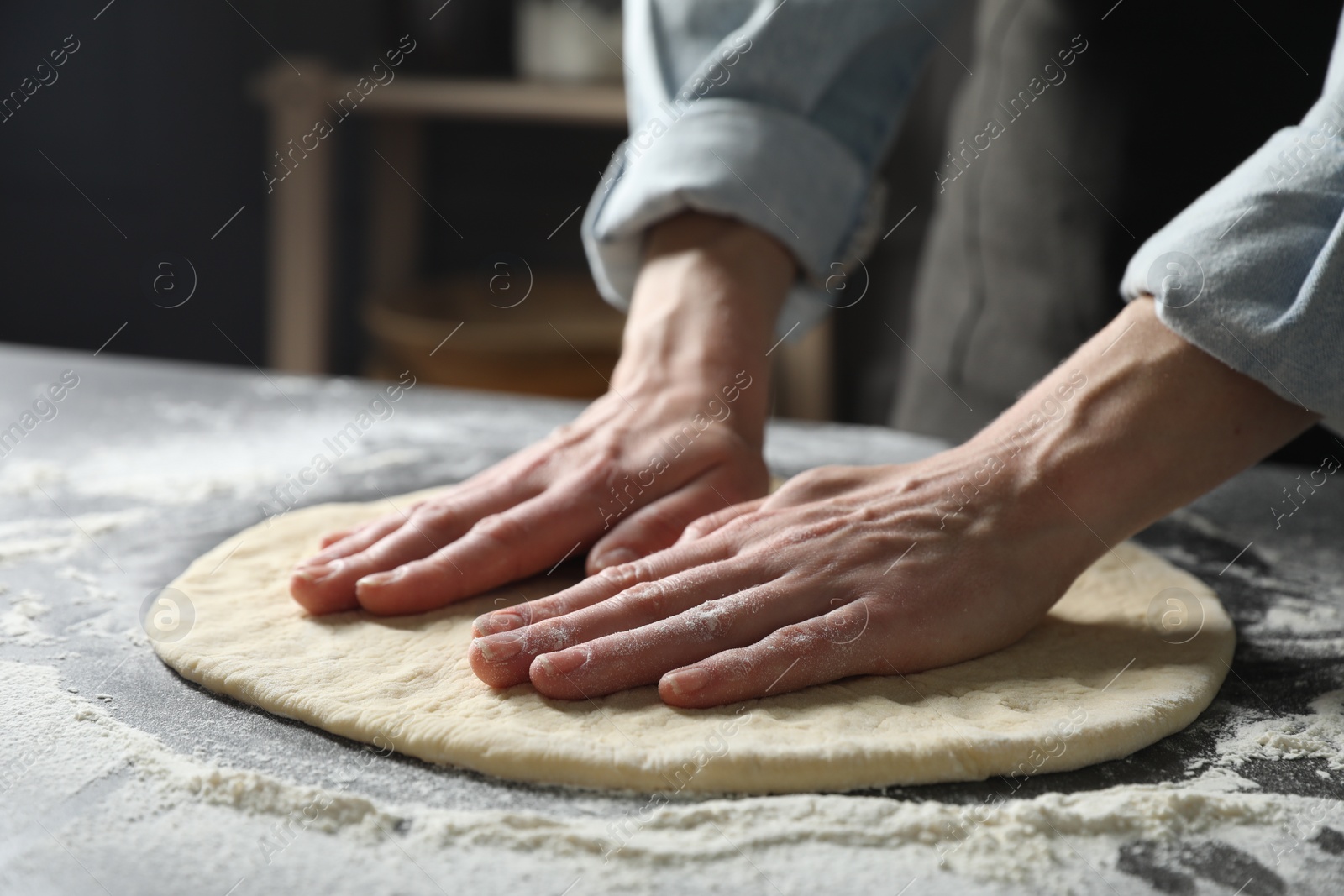 Photo of Woman making pizza dough at table, closeup