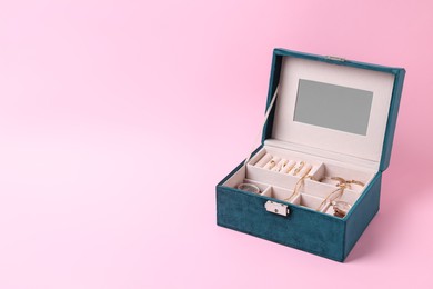 Jewelry box with many different accessories on pink background. Space for text