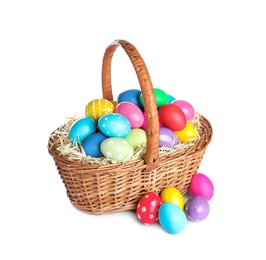 Wicker basket with bright painted Easter eggs on white background