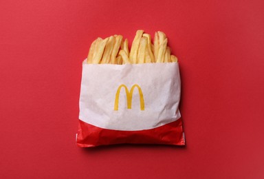 Photo of MYKOLAIV, UKRAINE - AUGUST 12, 2021: Small portion of McDonald's French fries on red background, top view