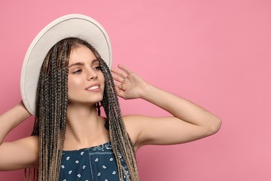 Photo of Beautiful woman with long african braids and hat on pink background, space for text