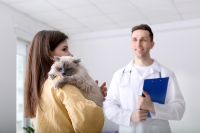 Young woman with cat and veterinarian in clinic