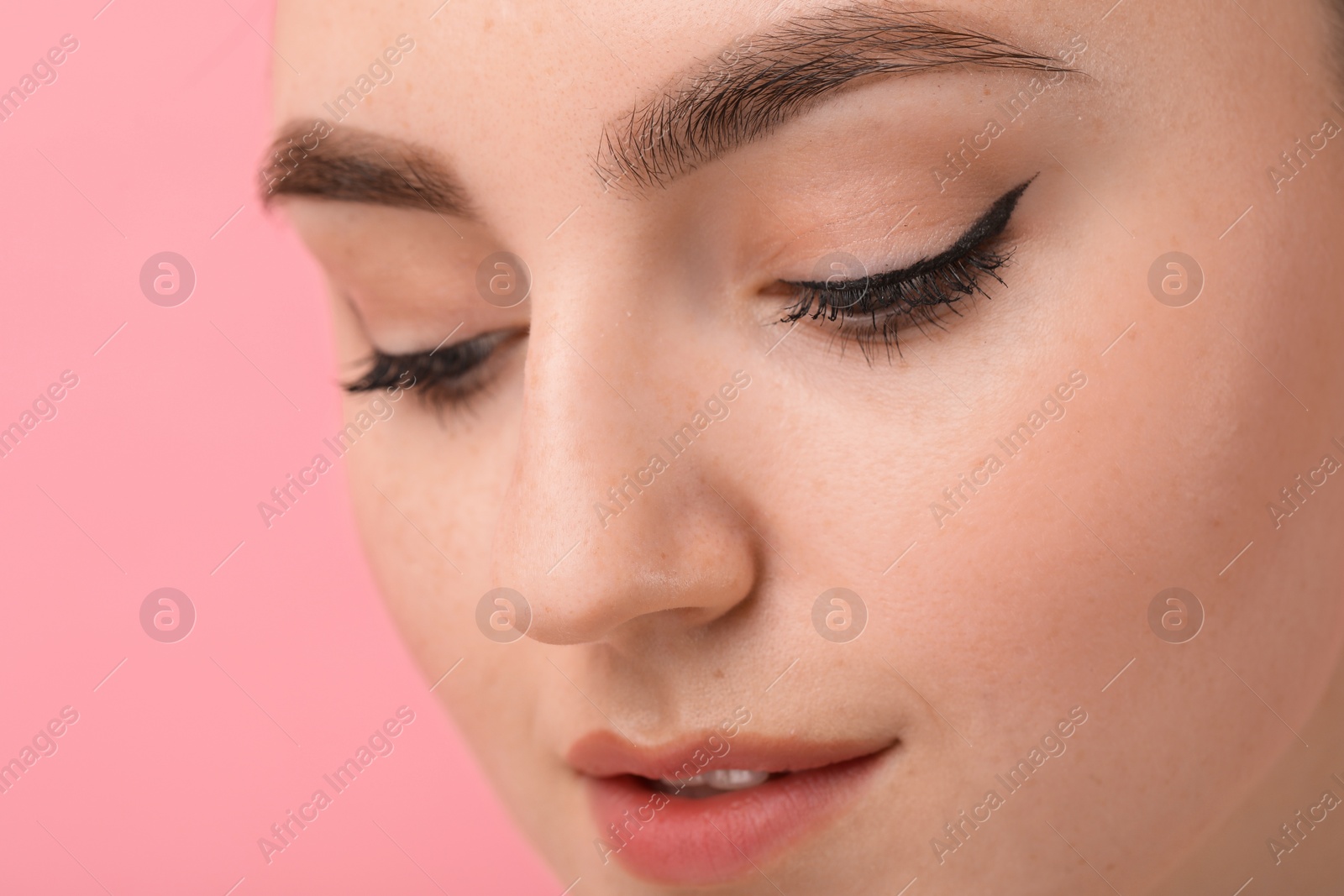 Photo of Makeup product. Woman with black eyeliner and beautiful eyebrows on pink background, closeup