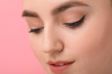 Makeup product. Woman with black eyeliner and beautiful eyebrows on pink background, closeup