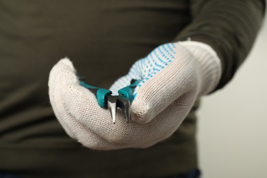 Photo of Man with bent nose pliers on light background, closeup