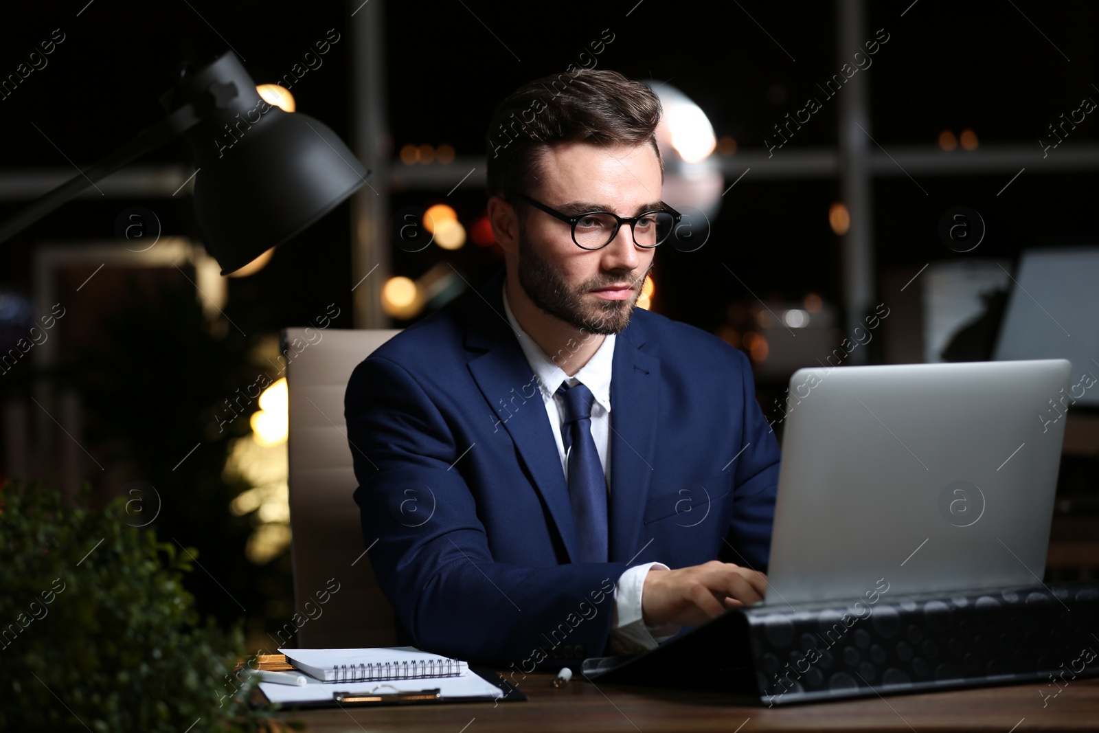 Photo of Young man working in office at night