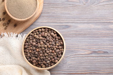 Photo of Ground pepper and corns on light grey wooden table, flat lay. Space for text