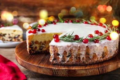 Image of Traditional Christmas cake decorated with rosemary and cranberries on table, closeup. Bokeh effect