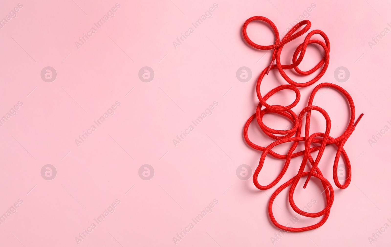 Photo of Red shoelaces on pink background, flat lay. Space for text