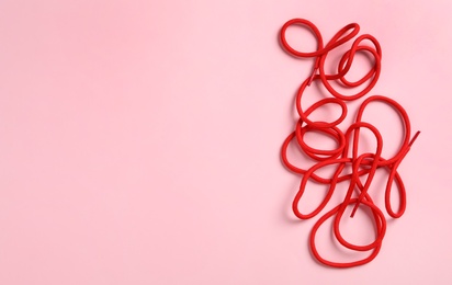 Photo of Red shoelaces on pink background, flat lay. Space for text