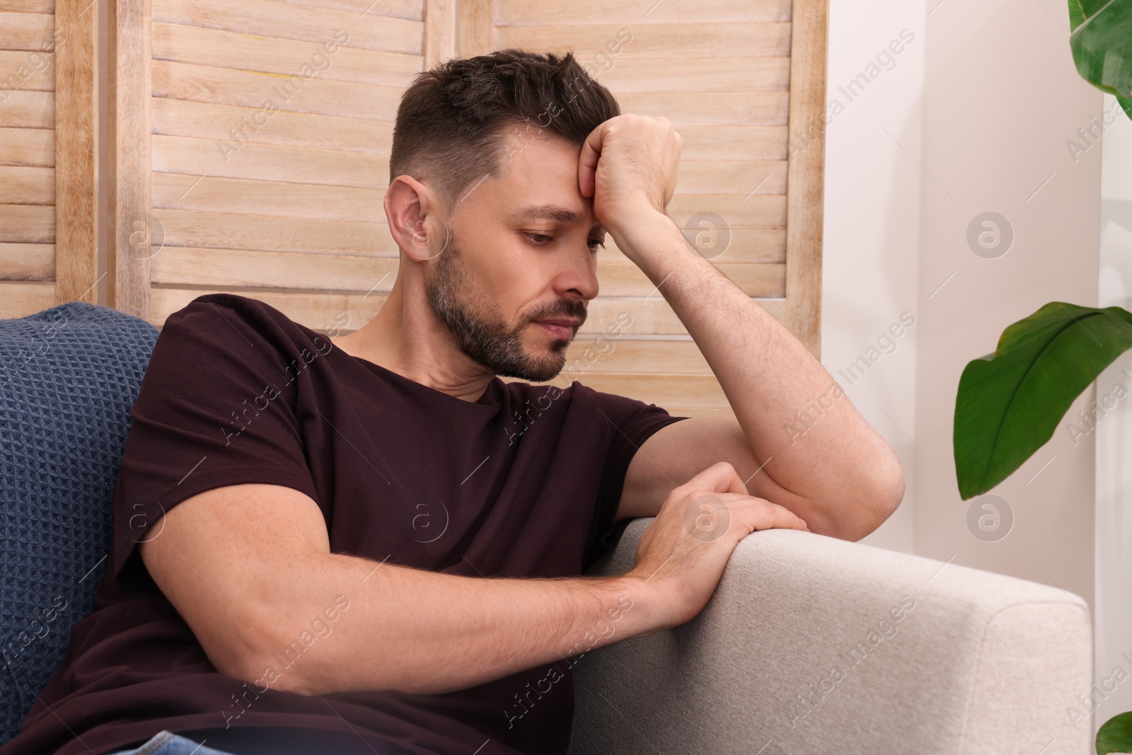 Photo of Upset man sulking on sofa at home. Loneliness concept