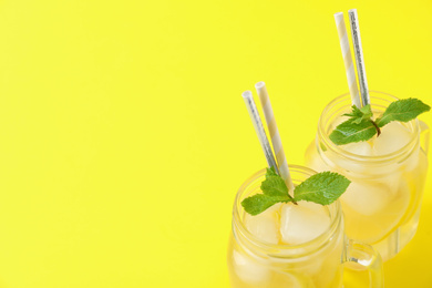 Photo of Closeup view of natural lemonade on yellow background, space for text. Summer refreshing drink