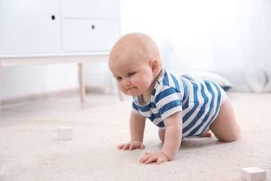 Photo of Cute little baby crawling on carpet indoors, space for text