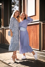 Photo of Beautiful young women in stylish blue dresses on city street