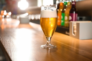Photo of Glass of beer on wooden table in pub