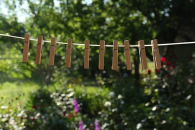 Photo of Wooden clothespins hanging on washing line outdoors